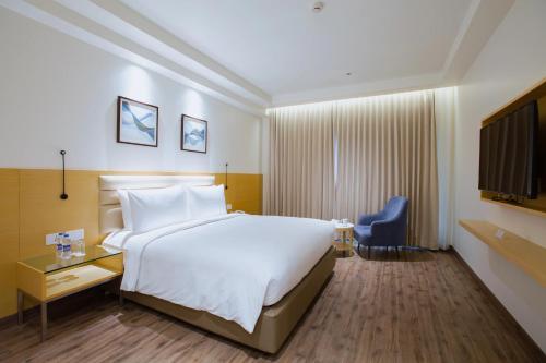 a hotel room with a large bed and a blue chair at IKON By Annapoorna in Coimbatore