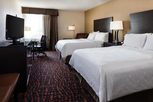 a hotel room with two beds and a flat screen tv at Holiday Inn Wichita East I-35 by IHG in Wichita
