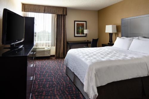 a hotel room with a bed and a flat screen tv at Holiday Inn Wichita East I-35 by IHG in Wichita