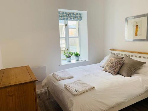 uma cama branca com duas almofadas e uma janela em Number Seven em Pembroke Dock