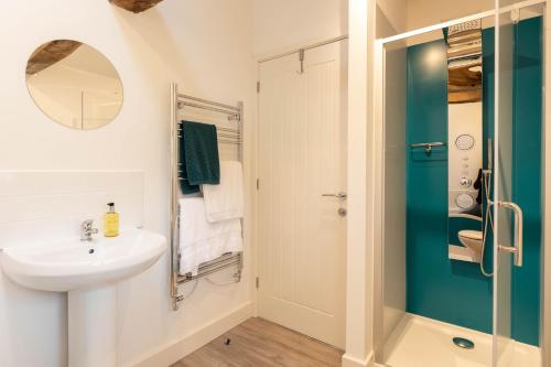 La salle de bains blanche est pourvue d'un lavabo et d'une douche. dans l'établissement Dyffryn Cottage - King bed, self-catering cottage with Hot Tub, à Denbigh