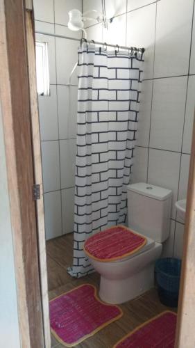 a bathroom with a toilet and a shower curtain at Pousada Margareth in Ilha do Mel