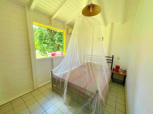 a bedroom with a bed with a mosquito net at Maison charmante à Sainte-Rose + Piscine in Sainte-Rose