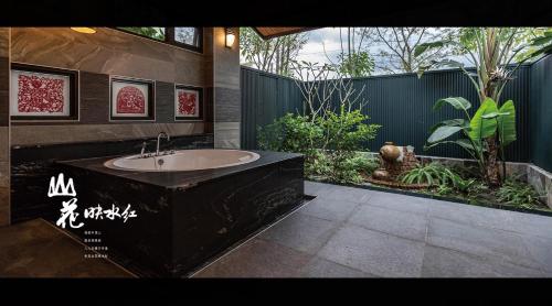 y baño con bañera grande y jardín. en 山花映水紅莊園民宿 en Yuemei