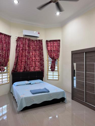 a bedroom with a bed and two windows at Teratak Anakanda in Kuala Berang