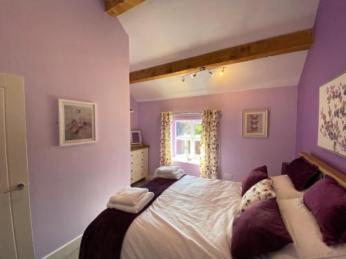 a bedroom with purple walls and a large bed at Blodyn Cottage - Cosy, Self-Catering with Private Hot Tub in Bodfari