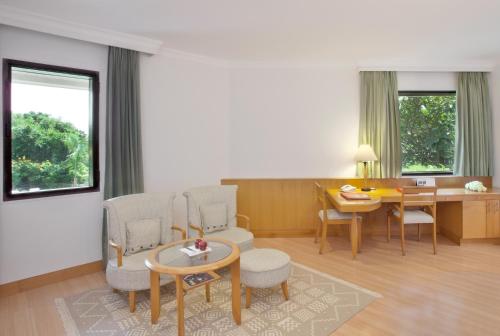 a living room with a table and chairs and a desk at Trident Chennai in Chennai