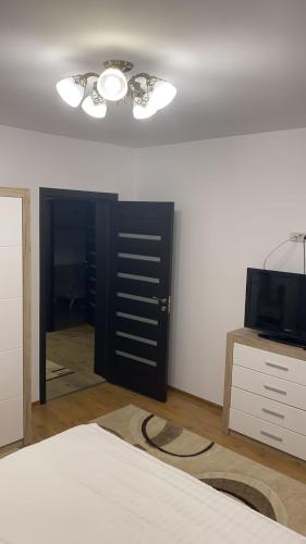 a bedroom with a bed and a black door and a television at Grant Apartament in Arad