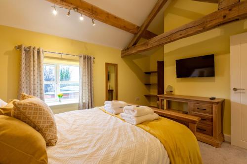 a bedroom with yellow walls and a bed with towels at Heulog Cottage - King Bed, Self-Catering with Private Hot Tub in Bodfari
