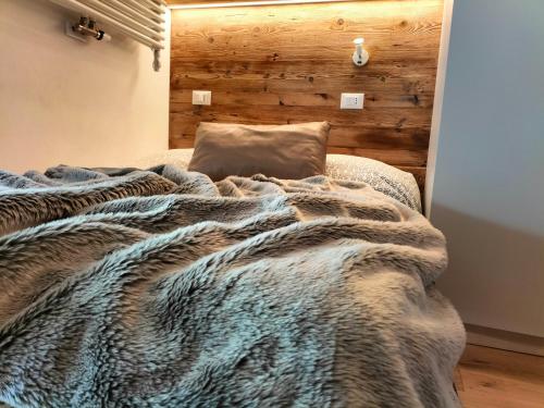 a bed with a blanket and a pillow on it at Appartamento Campiglio 2 in Madonna di Campiglio