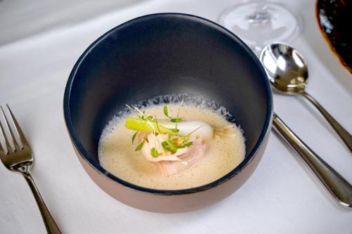 a bowl of soup on a table with a fork at Landhotel Heuvelzicht in Schin op Geul