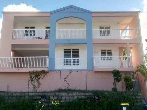 ein rosa und weißes Haus mit einem blauen in der Unterkunft Bas de villa , Résidence Venus calme, vue sur mer in La Trinité