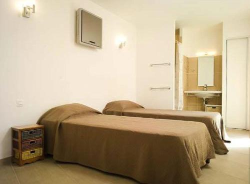 two beds in a room with a tv on the wall at Résidence A Rundinella in Porto-Vecchio