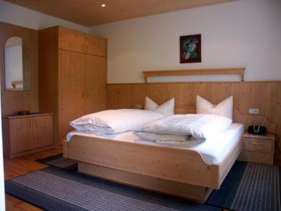 Un dormitorio con una gran cama de madera con almohadas blancas. en Gästehaus Meisl, en Berchtesgaden