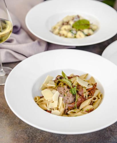 a plate of pasta with meat and cheese and a glass of wine at Dwór w Tomaszowicach in Modlnica