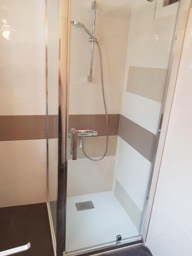 une douche avec une porte vitrée dans une salle de bain dans l'établissement DETENTE NATURE rando, ski , thermes, à Allevard