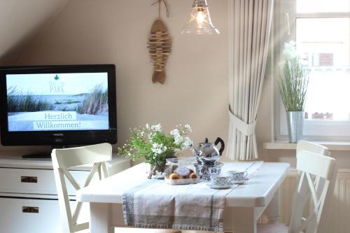 a dining room with a white table and a tv at Haus Gerd Janssen Wohnung 1 in Spiekeroog