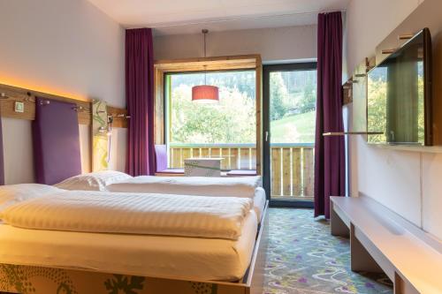 two beds in a room with purple curtains and a window at Explorer Hotel Bad Kleinkirchheim in Bad Kleinkirchheim