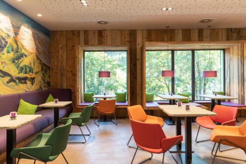a restaurant with tables and chairs and windows at Explorer Hotel Bad Kleinkirchheim in Bad Kleinkirchheim
