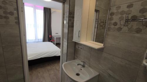 een badkamer met een wastafel en een slaapkamer met een bed bij Rybalsky Studio Apartment Podil - Dnipro View in Kiev