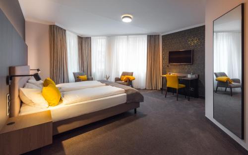 ein Schlafzimmer mit einem großen Bett mit gelben Kissen in der Unterkunft Hotel Am Markt Nordenham in Nordenham