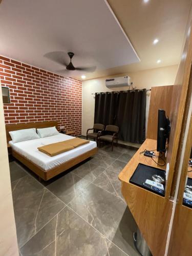 a bedroom with a bed and a brick wall at Hotel Vardhan in Silvassa