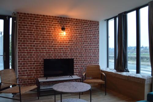 sala de estar con pared de ladrillo y TV de pantalla plana en "Gîte Le Relais Viennois" vue sur Loire & linge inclus en Blois