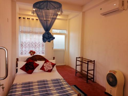a bedroom with a bed with red pillows and a window at KNT Villa in Weligama