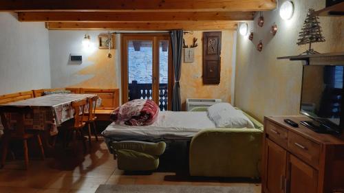 a room with a bed and a dining room with a table at Maisonnette de montagne in Ollomont