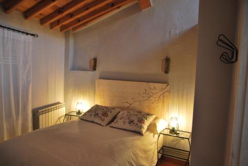 1 dormitorio con 1 cama blanca y 2 lámparas en El Arroyo, en Los Narros