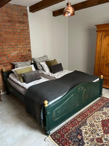 a green bed in a room with a brick wall at Uroczysko Oleśnica in Chodzież