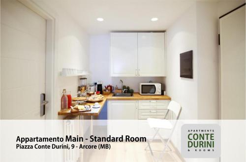 a kitchen with white cabinets and a table and a microwave at Conte Durini Apartments & Rooms in Arcore
