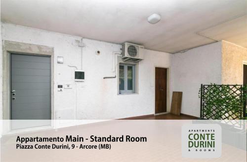 a white house with a garage door and a window at Conte Durini Apartments & Rooms in Arcore
