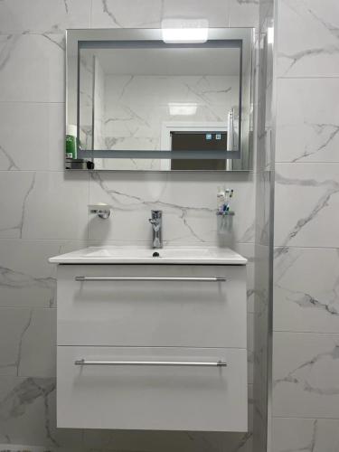 a white bathroom with a sink and a mirror at Emily & Nasi in Plovdiv