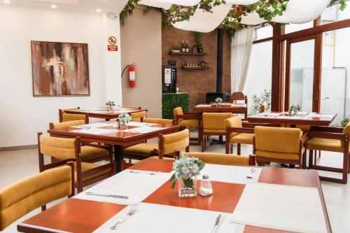 a restaurant with wooden tables and chairs and windows at REEC Latacunga by Oro Verde Hotels in Latacunga