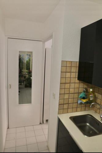 - une cuisine blanche avec un évier et un miroir dans l'établissement Azzurra, à Beausoleil