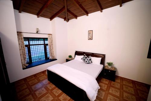 a bedroom with a white bed and a window at Sky touch cottage & stays in Mukteswar