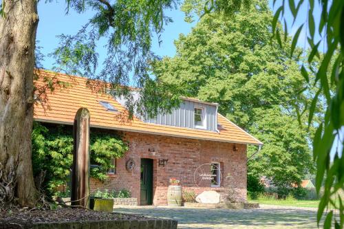 an old brick house with a tree in the foreground at Landhäuschen Anderswo in Bocholt