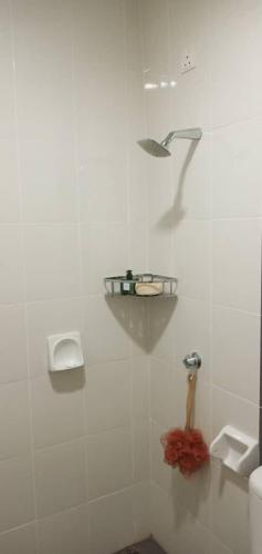 a white tiled bathroom with a toilet and a sink at 7eVenKitchen Hmestay in Jitra