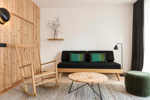 a living room with a black couch and a chair at Hotel Tyrol in Funes