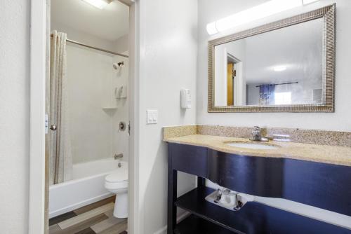 a bathroom with a sink and a mirror and a toilet at Adams Inn in Dothan