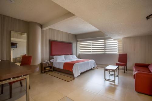 Habitación de hotel con cama, mesa y sillas en Hotel Puente Real, en Puebla