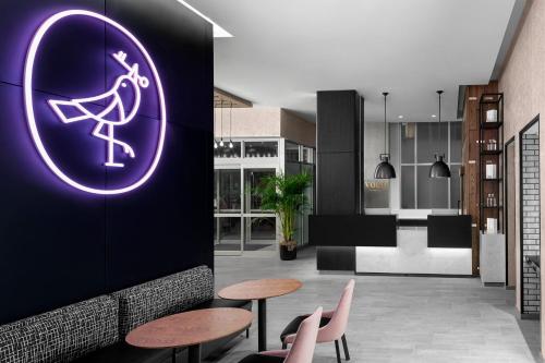 Una habitación con dos mesas y un cartel morado en una pared. en voco Times Square South New York by IHG, en Nueva York