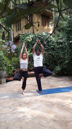 a man and a woman doing yoga in front of a house at Eco Village Yoga Home in Digana