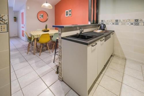 una pequeña cocina con fregadero y mesa en L'escapade, maison de village classée meublé de tourisme 4 étoiles, en Marseillan