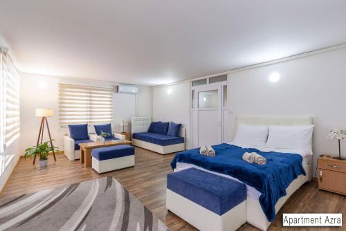 a bedroom with a blue bed and a couch at Pansion Beg in Tuzla