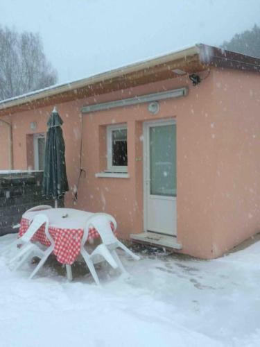 une table et des chaises dans la neige devant une maison dans l'établissement Le Coin Tranquille au pied du Puy de Dôme, à Pontgibaud