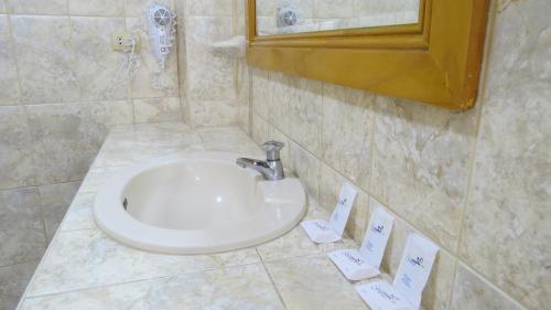 ein Badezimmer mit einem weißen Waschbecken und einem Spiegel in der Unterkunft Hotel Las Flores in Ica