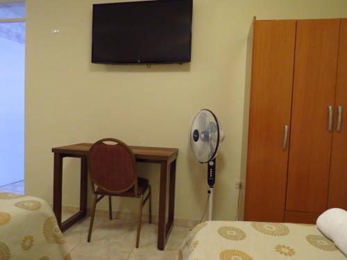 a room with a desk with a fan and a chair at Hotel Las Flores in Ica