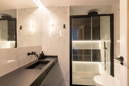 ein weißes Bad mit einem Waschbecken und einer Dusche in der Unterkunft Salado Triana Suites by Valcambre in Sevilla
